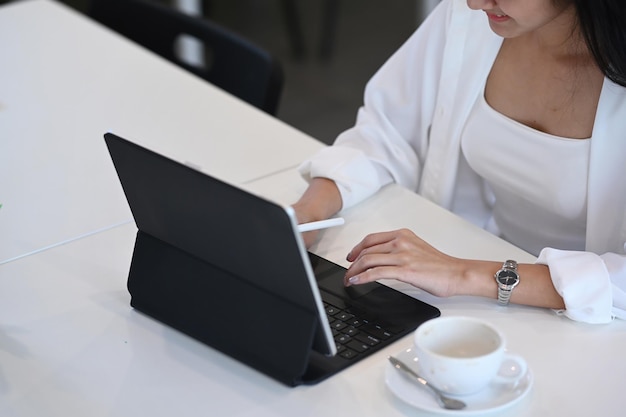 Young female freelance in casual wear working with computer tablet at coffee shop.