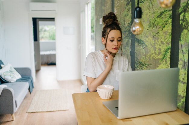 写真 ラップトップに取り組んでいる若い女性のフリーランサー彼女はカメラでコンテンツを作成し、ラップトップに取り組んでいます