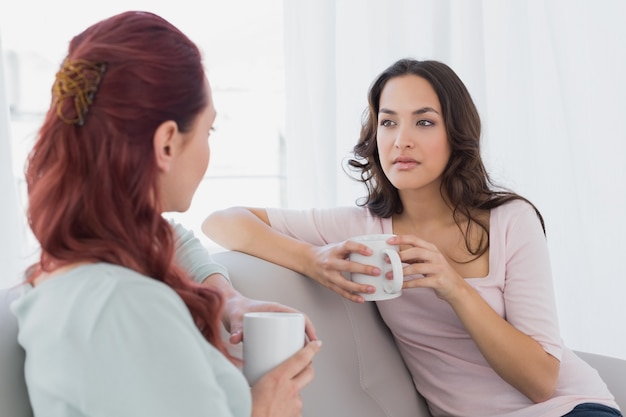 young female friends chatting over coffee at home