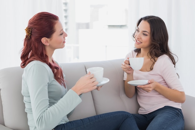 Giovani amici femminili che chiacchierano sopra il caffè a casa