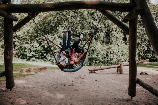 Foto giovani amiche che si godono l'altalena nel parco giochi