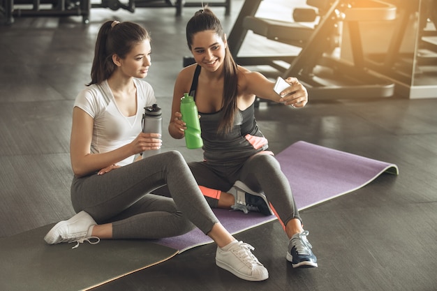 Young female friends exercise in the gym taking photos