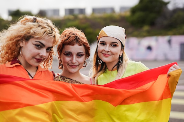 프라이드 퍼레이드에서 LGBT 무지개 깃발을 들고 있는 젊은 여자 친구들