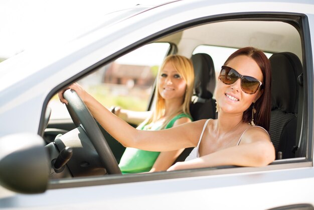 young female friends sitting in car, and ready for vacation.