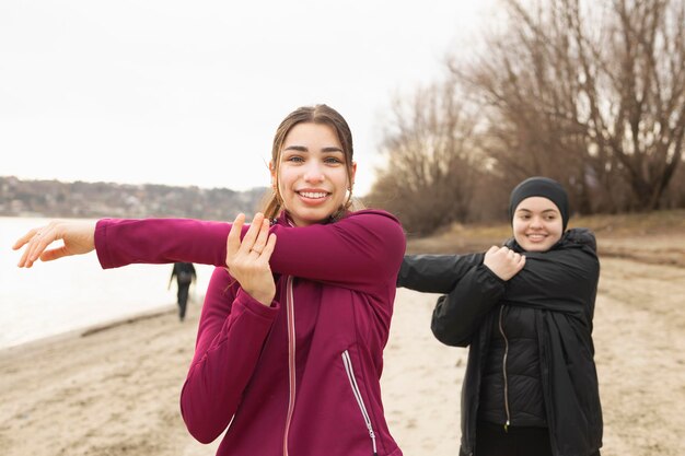 Young female friends stretching their arms before their morning training