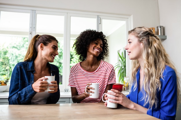 コーヒーのマグカップを押しながら話している若い女性の友人