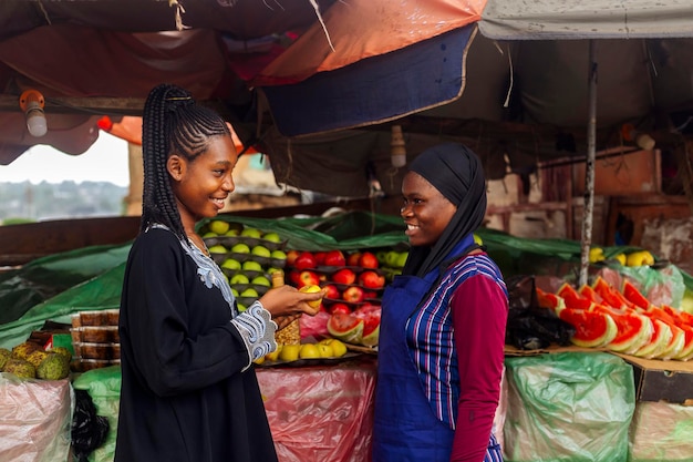 young female fruit merchant on blue apron attending to buying client