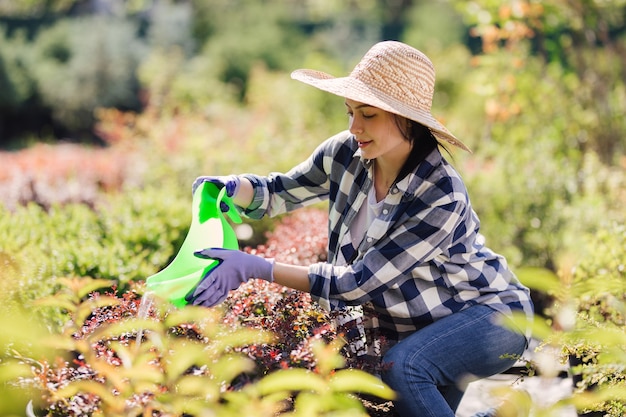 庭の植物に水をまく若い女性の庭師。