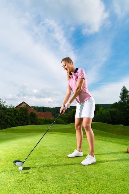 Young female golf player on course doing golf swing