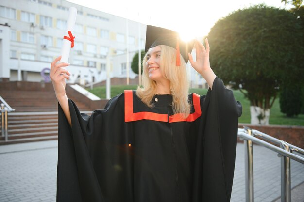 Foto una giovane laureata sullo sfondo dell'università