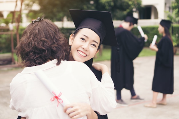 사진 졸업식, 성공, 목표에 그녀의 어머니를 포옹하는 젊은 여성 대학원. 교육 개념.