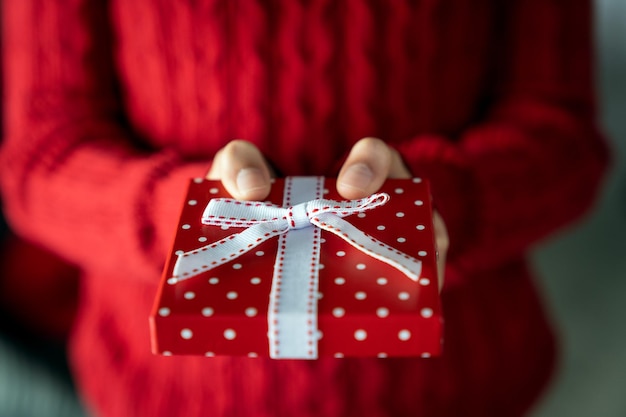 Young female hands holding gift box with ribbon