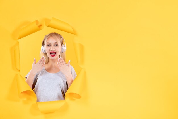 Giovane femmina in cuffie su carta gialla strappata audio di sfondo audio ultrasuoni musica