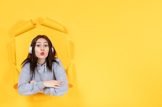 young female in headphones on a torn yellow paper background music ultrasound sound audio