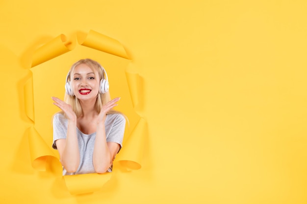 Young female in headphones on yellow wall