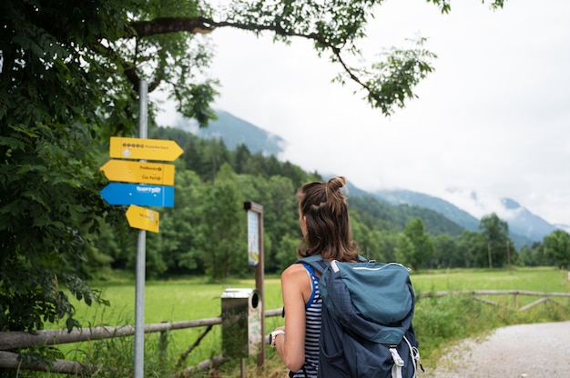 Young female hiker with a backpack looking at a signpost deciding which way to go.