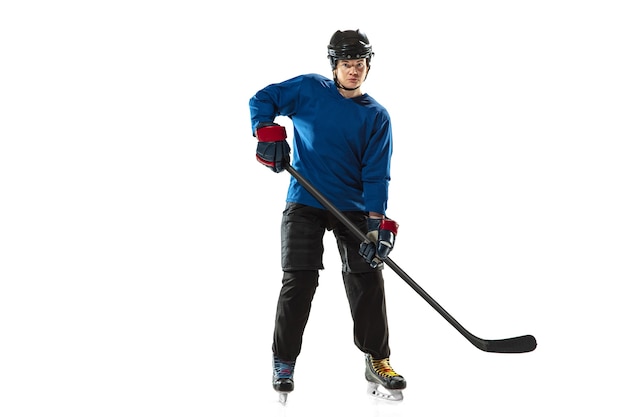 Giovane giocatore di hockey femminile con il bastone sul campo da ghiaccio e sul muro bianco. sportiva che indossa l'attrezzatura e l'allenamento del casco. concetto di sport, stile di vita sano, movimento, azione, emozioni umane.
