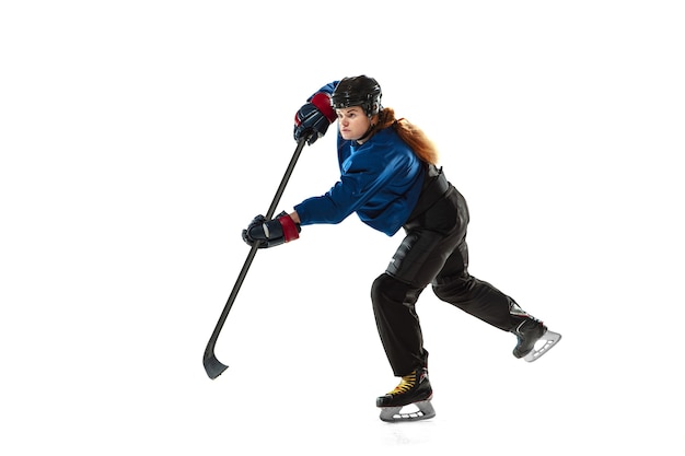 Young female hockey player with the stick on ice court and white wall