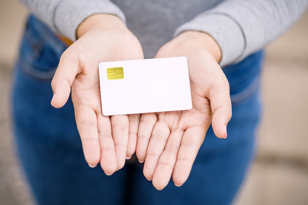 Young female holding blank credit card, outdoor