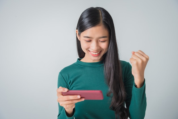 Young female holds smartphone and showing fist