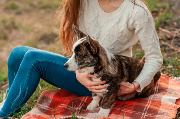 秋の公園でウェールズのコーギー犬を抱き締める若い女性