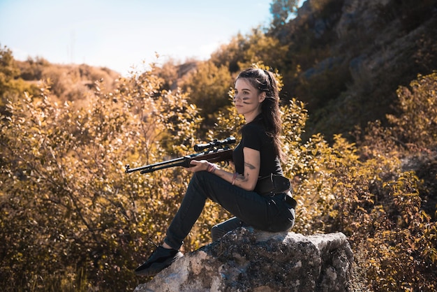 Photo young female hunter in top with a rifle in summer at nature
