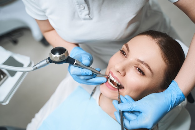 young female is lying in dental chair during procedures for healing her teeth with equipment