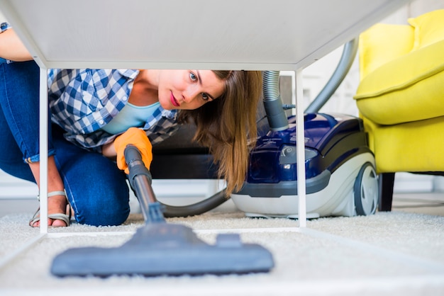 Photo young female janitor cleaning carpet with vacuum cleaner