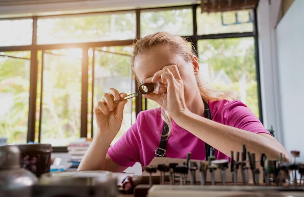 Young female jeweler making jewelry in workshop