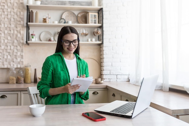 A young female journalist writer blogger works remotely from home using a laptop online sitting in