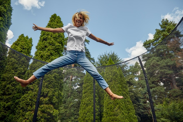 Young Female Jumping On Trampoline Outdoors