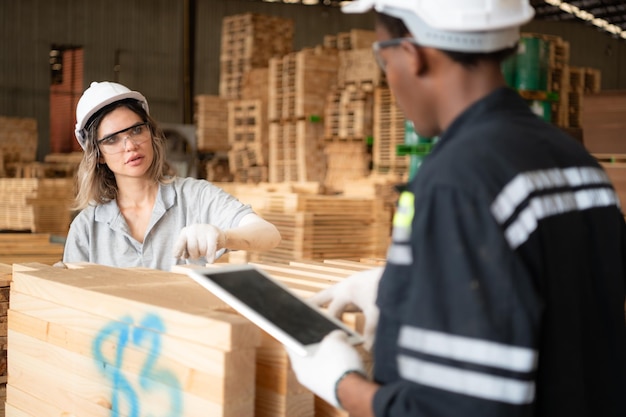 Young female and male warehouse workers using digital tablet for working in wooden factory Checking