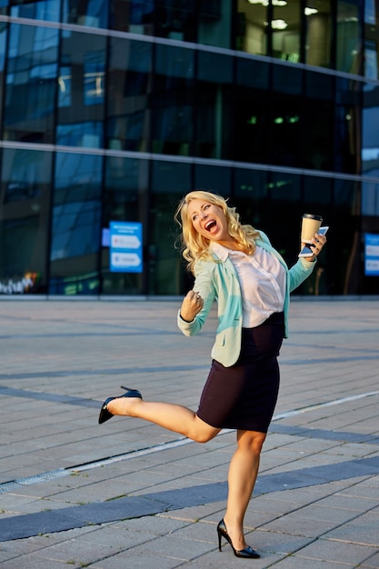 Photo young female manager stands outside with cup of coffee