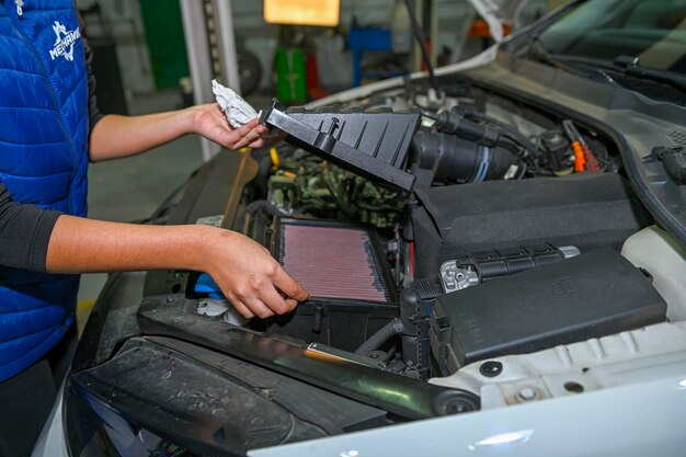 Photo young female mechanic checking the air filter of a car engine