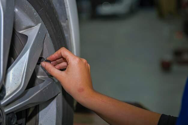 車のタイヤの空気圧をチェックする若い女性整備士