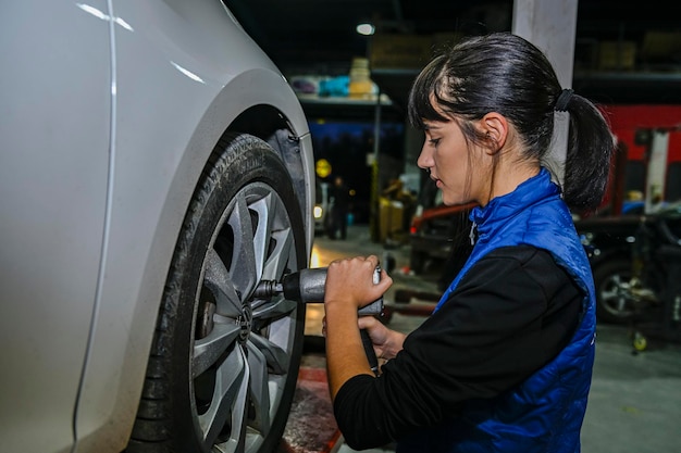 車のタイヤの空気圧をチェックする若い女性整備士