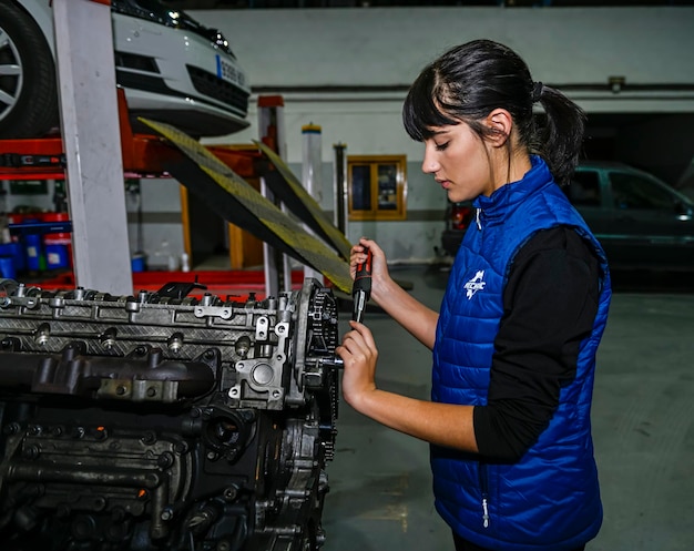 Young female mechanic working on the repair of a car engine