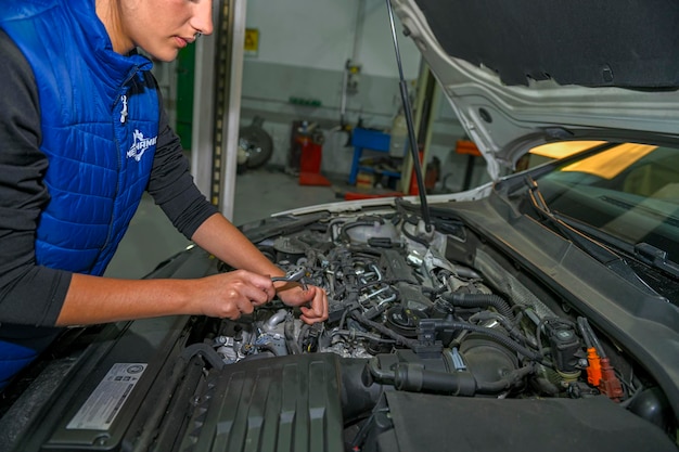 Young female mechanic working on the repair of a car engine