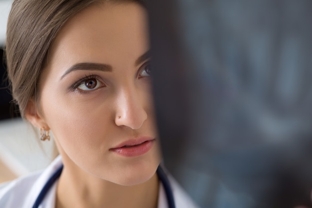 Young female medical doctor or intern looking at lungs x ray image standing at her office. Radiology, healthcare, medical service or education concept. Close up shot