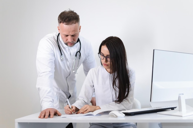 Young female medical worker consults with the male head physician. Two doctors in the office