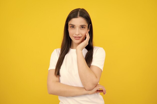 Young female model face Pretty joyfully female model looking with satisfaction Studio portrait of looking beautiful woman isolated against yellow background