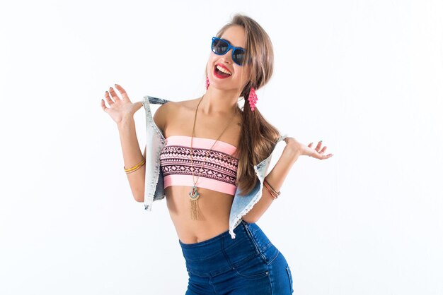 Young female model standing sideways bending her body putting arm on hip wearing sunglasses and bright accessories