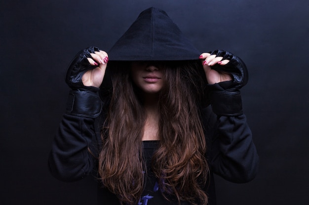スポーツフード付きスウェットシャツ黒の背景を身に着けている若い女性モデル