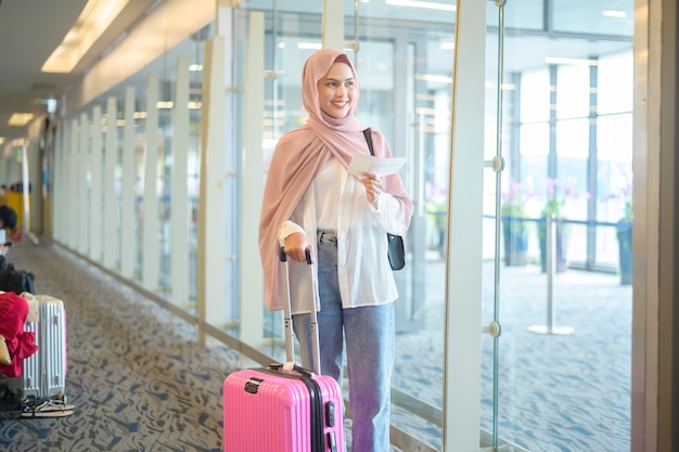 국제 공항에서 가방을 들고 젊은 여성 이슬람 여행자