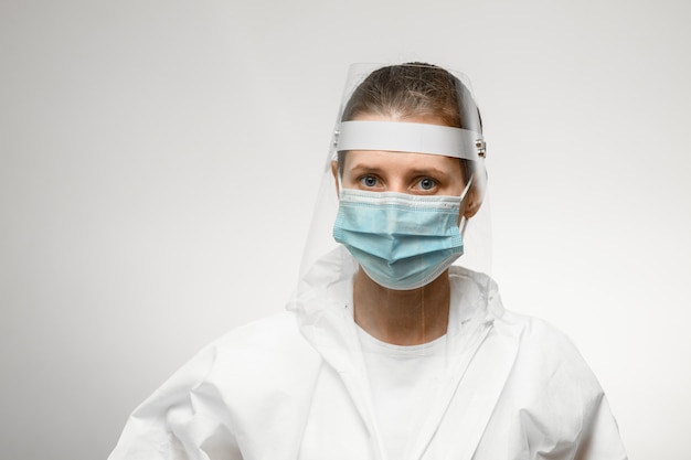 Photo young female nurse in medical mask and protective shield on her head