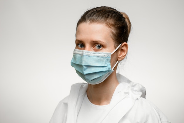 Young female nurse in medical mask which looking aside.