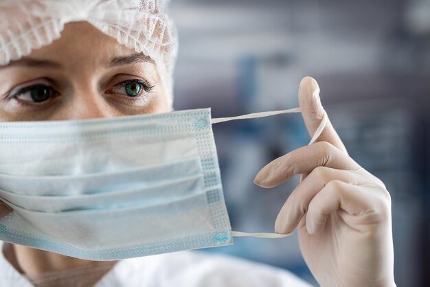 Молодая медсестра надевает медицинскую маску на операционную