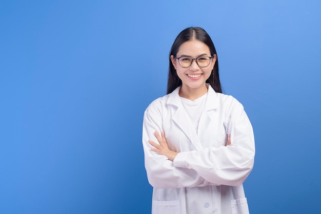 A young female ophthalmologist with glasses holding eye chart over blue wall, healthcare concept