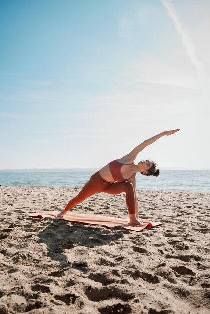 주황색 탑과 레깅스가 확장 된 측면 각도 포즈를 연습하는 젊은 여성 (Utthita Parsvakonasana)