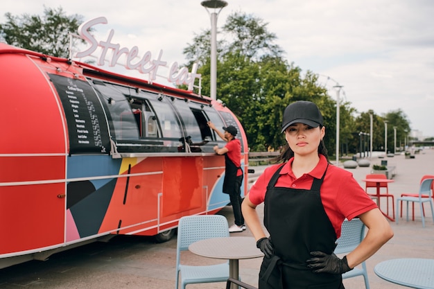 Photo young female owner of food truck standing in front of camera